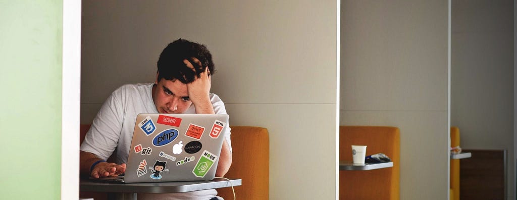 Man with his head in his hand, staring at a laptop