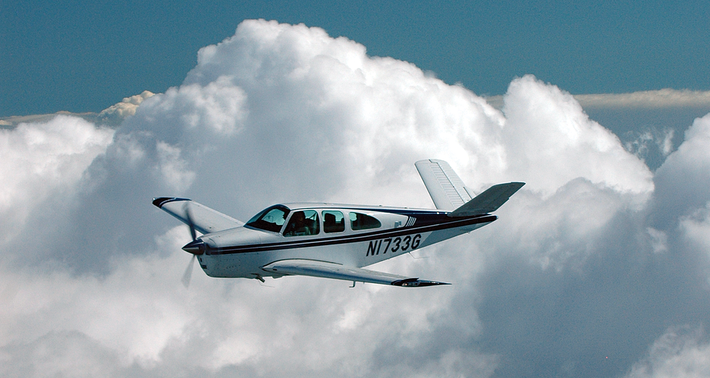 Photo of a small airplane flying in the clouds.