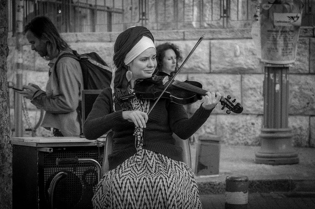 black and white image of a woman playing violin outdoors