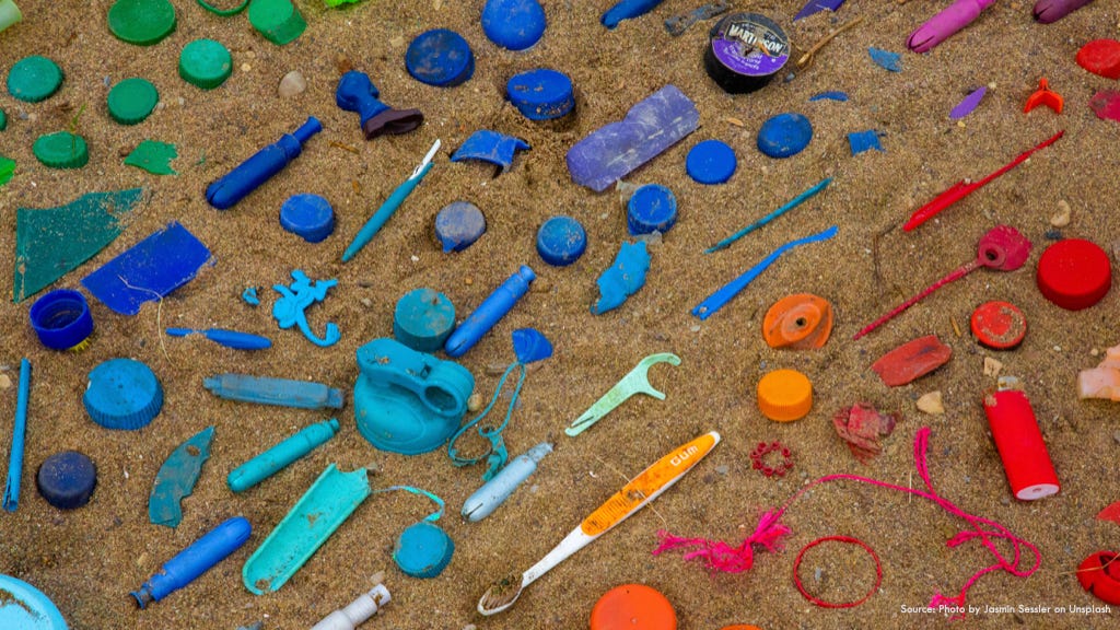 Photo of plastic collected from the ocean and laid out along the beach sorted by colour.