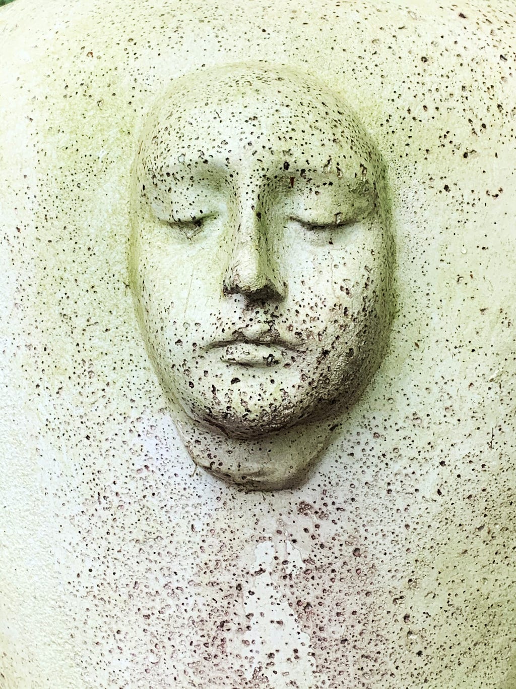 A sculpted face against a faded white background.