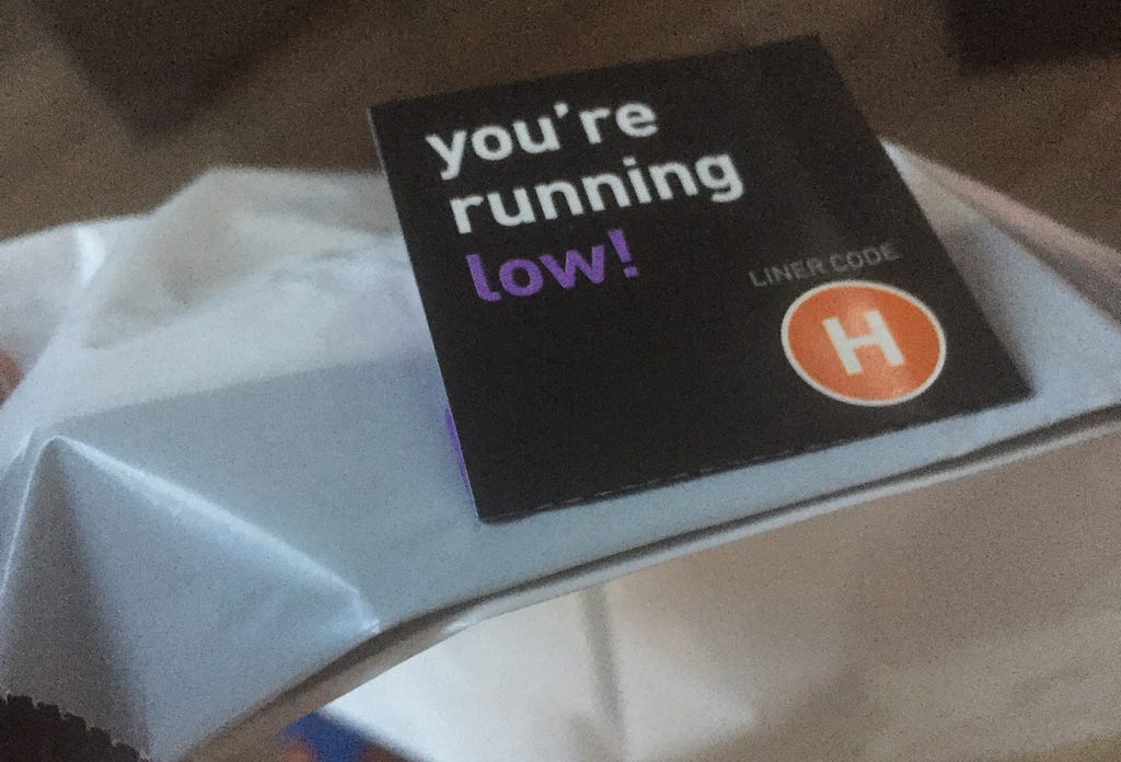 A close-up photo of a label attached to a trash bag that says “you’re running low!”