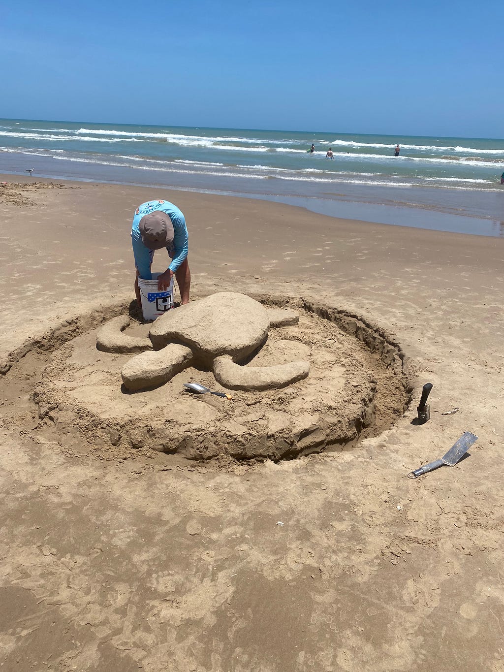 A man sculpting a sea turtle out of sand.