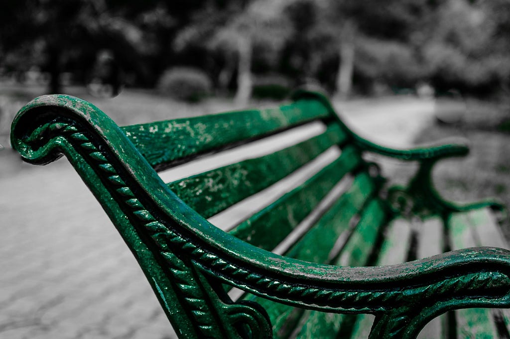 A green metal bench with peeling paint