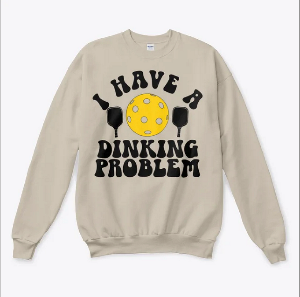 White sweatshirt reading “I have a dinking problem” with an image of a pickleball and paddles.