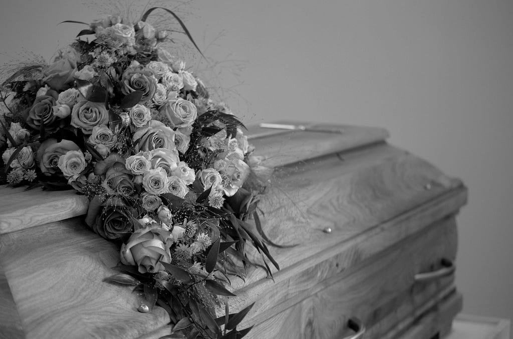 black and white photo of coffin with flowers on top