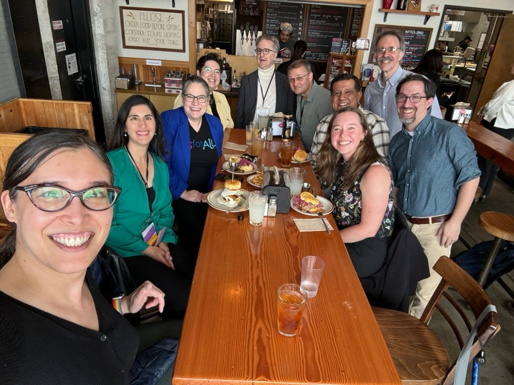 A selfie with 10 SIGCSE attendees around a long wooden table with biscuit sandwiches.