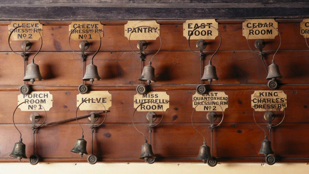 10 labelled bells against a wooden panel, named things like Cleeve Dressing Rm 2, East Door, King Charles’ Dressing Room