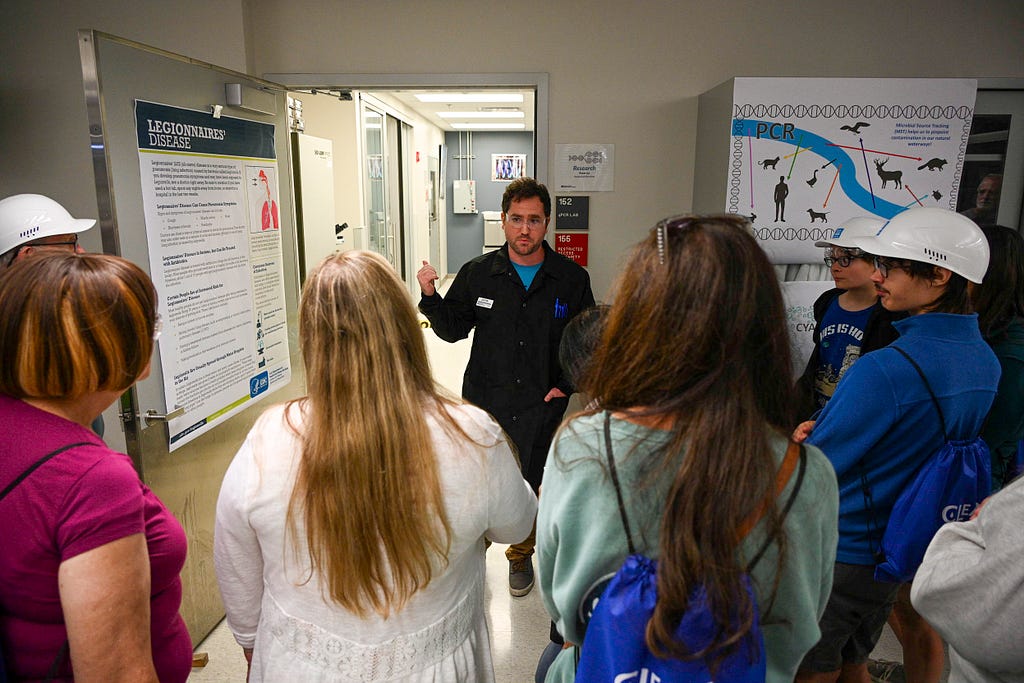 Justin Seikel speaks to tour participants in front of some charts in the Sewer District lab.