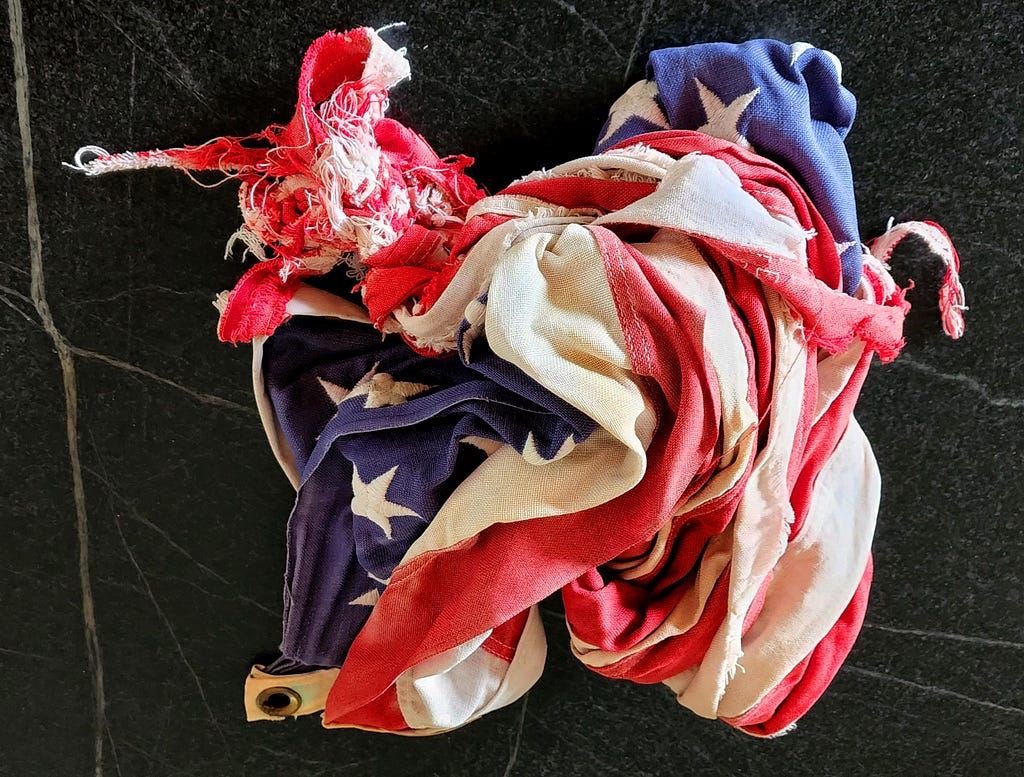 Contorted and worn American flag on a black background with white streaks.