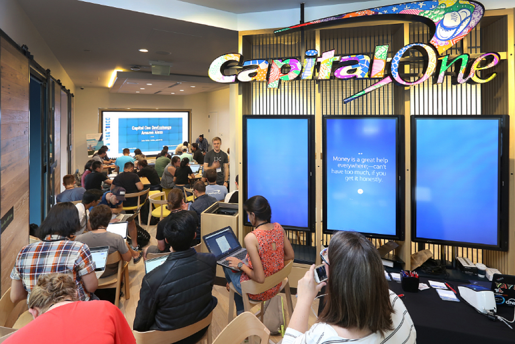 Capital One Cafe full of several dozen people sitting on folding chairs using their laptops