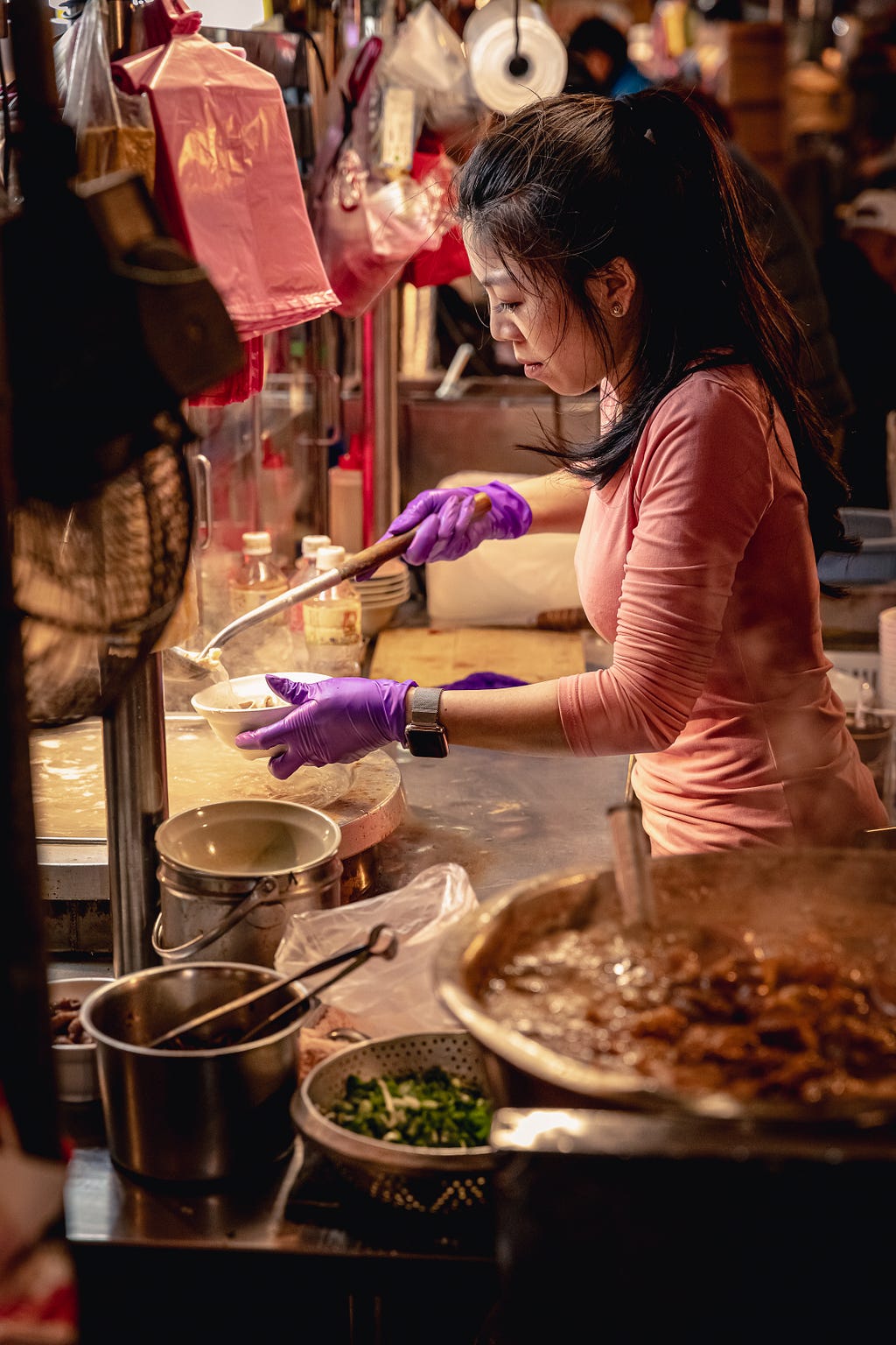 a gorgeous street vendor preparing a portion of soup for one of her customers at a night market food stall