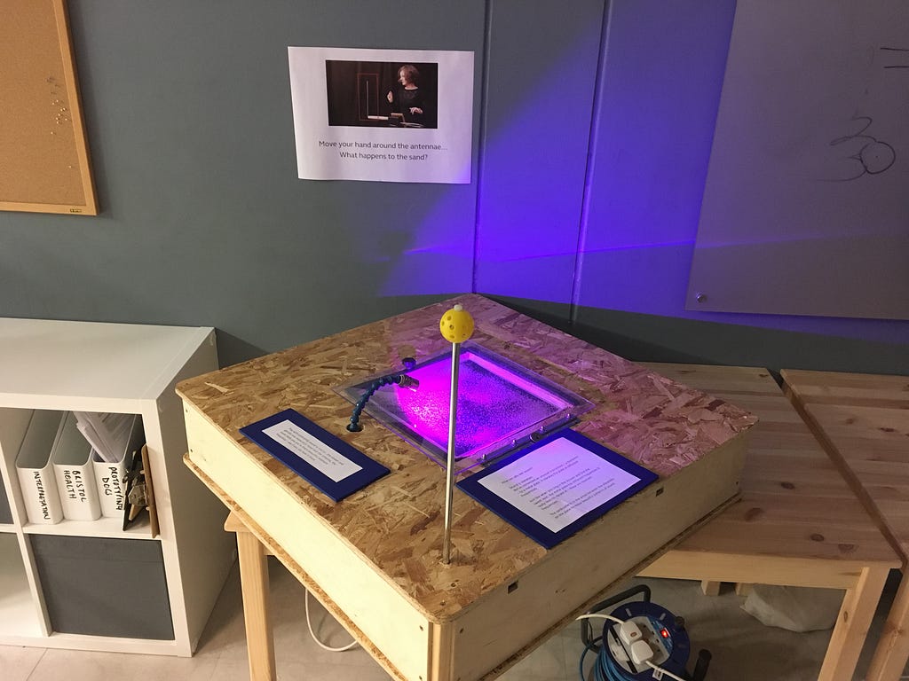 Image: Early concept prototyping for sand exhibits — wooden table with signage and lights