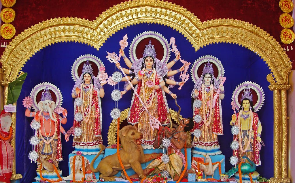 Image of the three forms of Divine Feminine. The center form — Durga — is shown to be killing the demon Mahishasura.