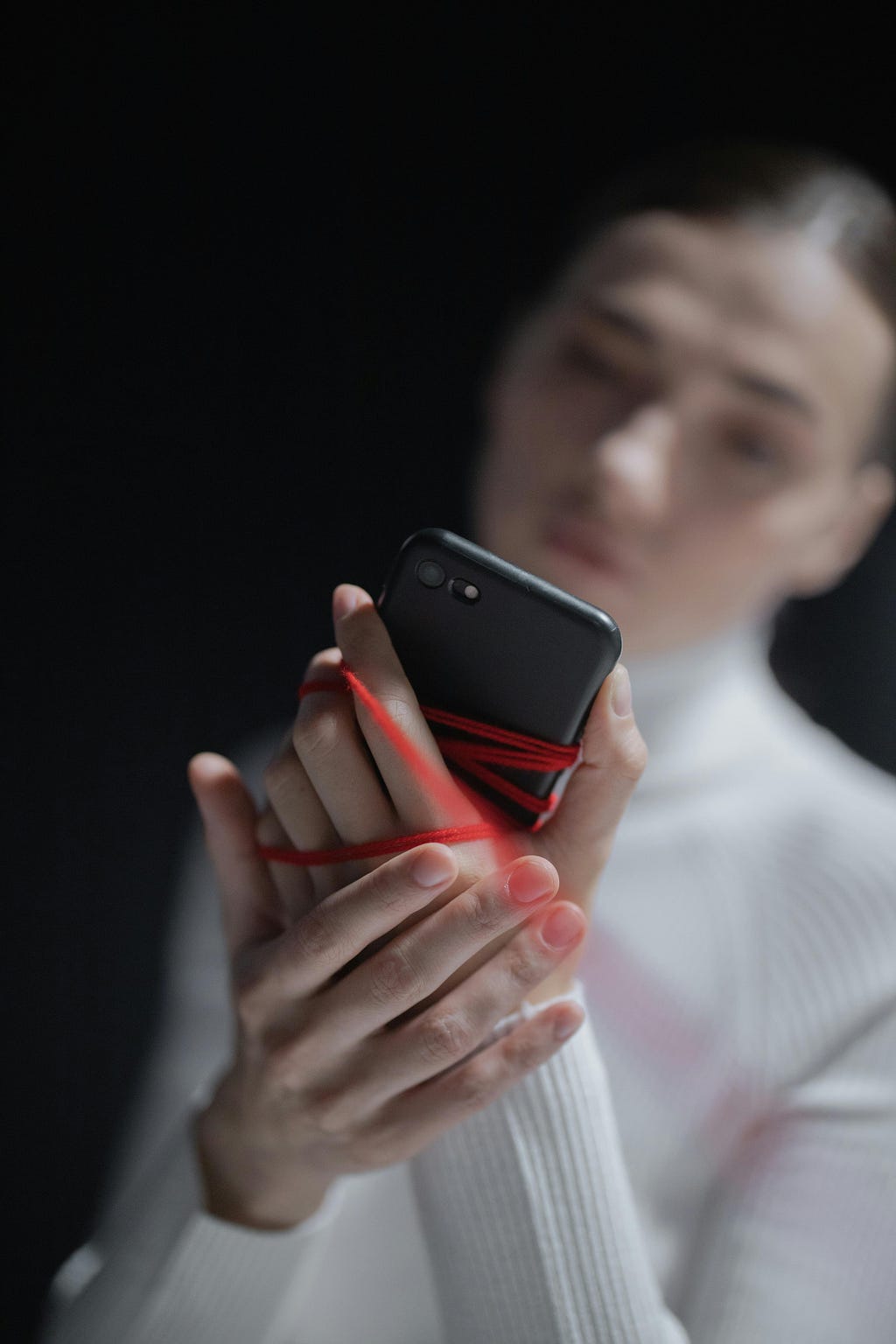 Photo by cottonbro studio: https://www.pexels.com/photo/woman-with-smartphone-tied-to-hand-with-red-thread-7670139/