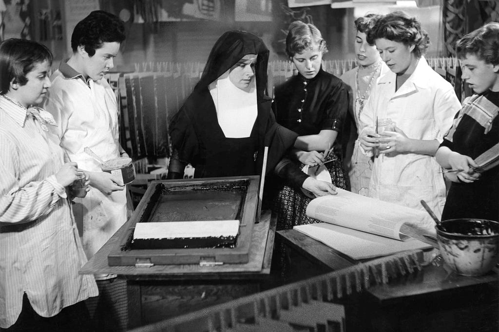 Photograph of Sister Corita and her students with serigraphy machine, continues working and teaching at IHC, her reputation as an artist and teacher growing.