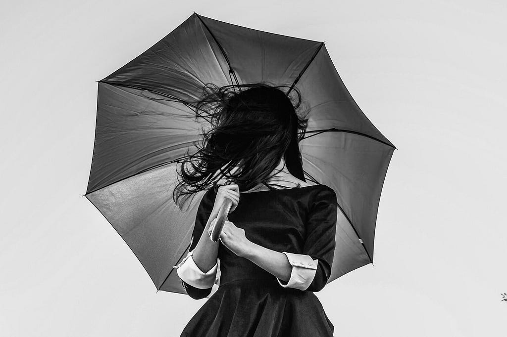 a woman in a black dress, holding an umbrella