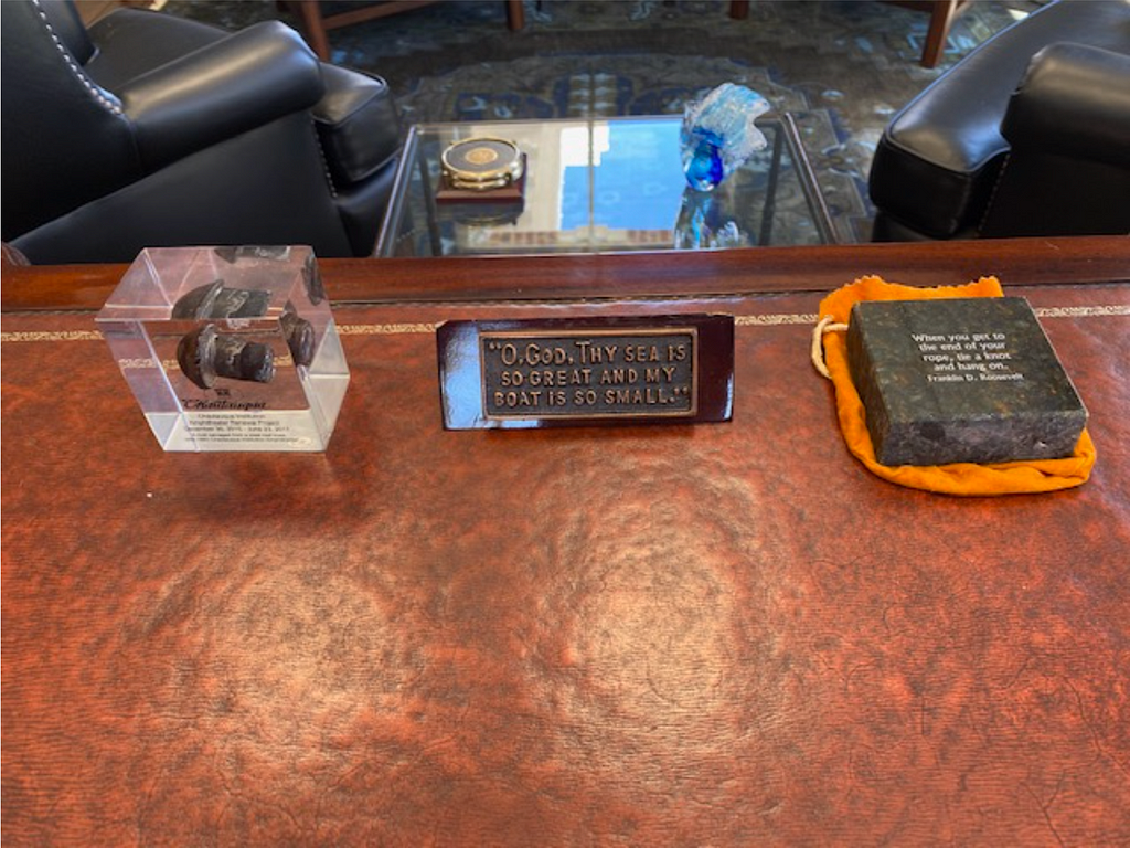 Three items on President Michael Hill’s desk in the Colonnade on the Chautauqua grounds: A rivet, and quotes by JFK and FDR.
