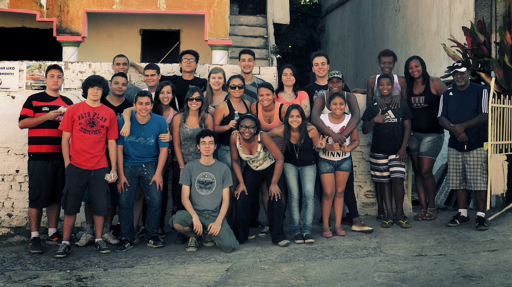 Grupo de mais de 20 pessoas posando para foto na calçada em frente à casa.