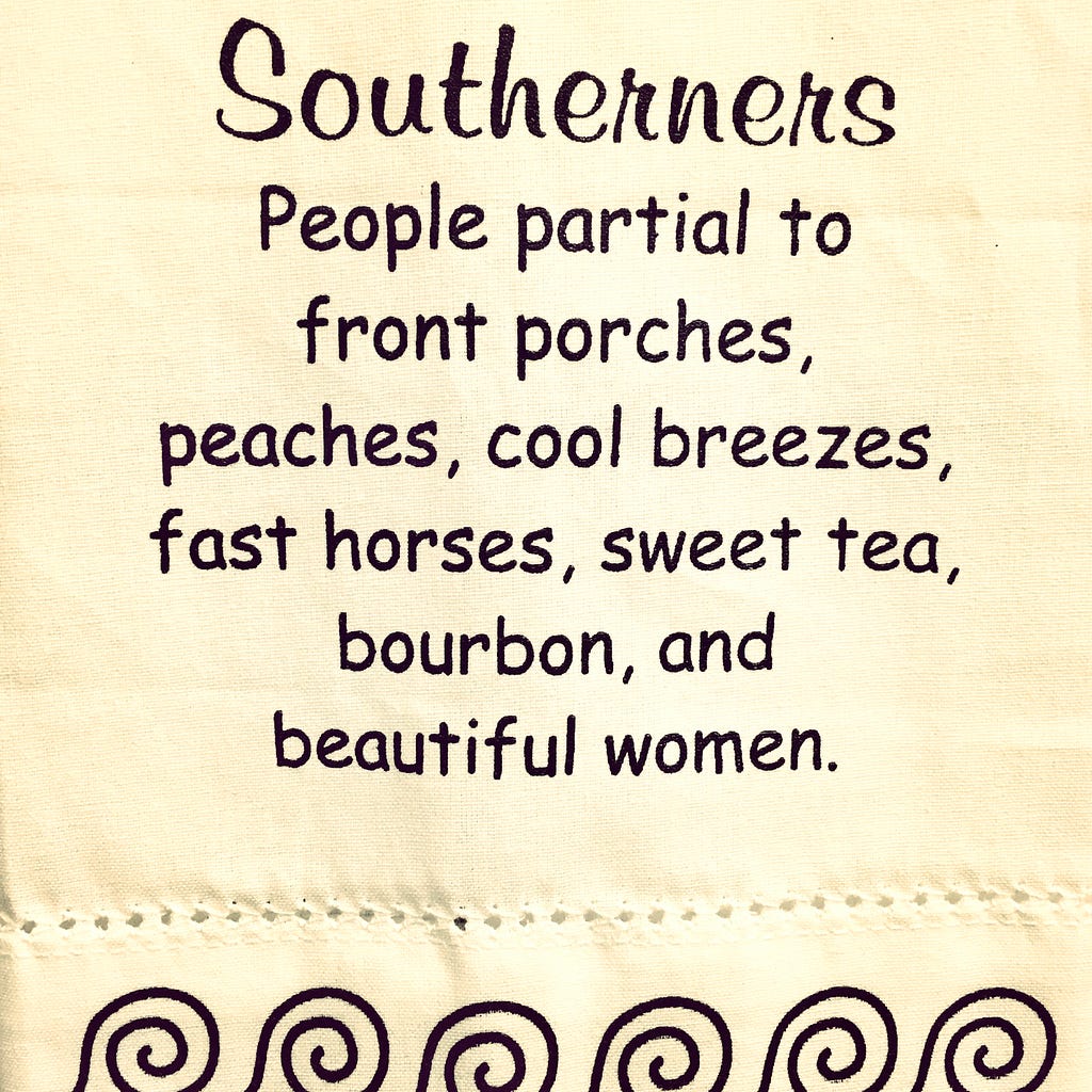 Image of a cream cloth with small round stiches dotting the bottom crease, with black-printed circular waves cresting to the right across the bottom and black writing stating top to bottom of the linen: “Southerners People partial to front porches, peaches, cool breezes, fast horses, sweet tea, bourbon, and beautiful women.”