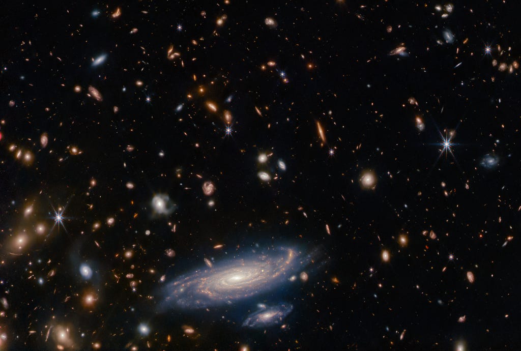 Image of thousands of galaxies of many shapes, colors, and sizes against a black background.