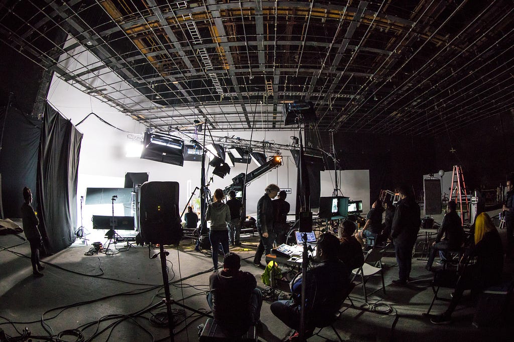 A large indoor film set with the film crew working in it.