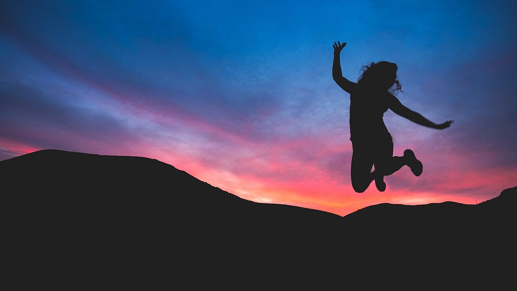 Silhouette of a woman jumping for joy at dawn