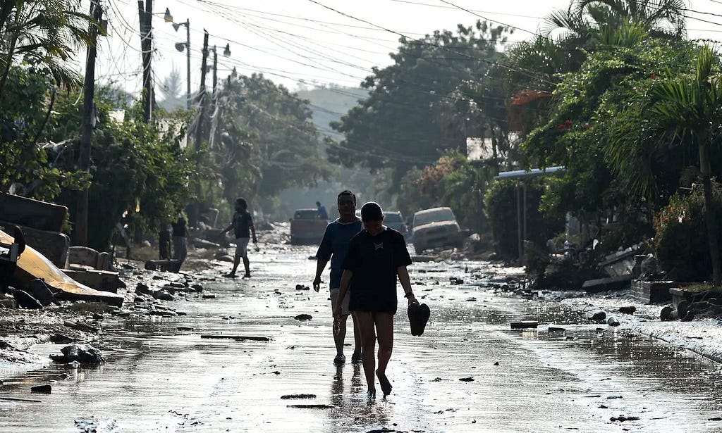 People walk along a street in Planeta, municipality of La Lima, Honduras one of the hardest hit communities by category 4 hurricane “Eta” in 2020 . Photograph: Orlando Sierra/AFP/Getty Images