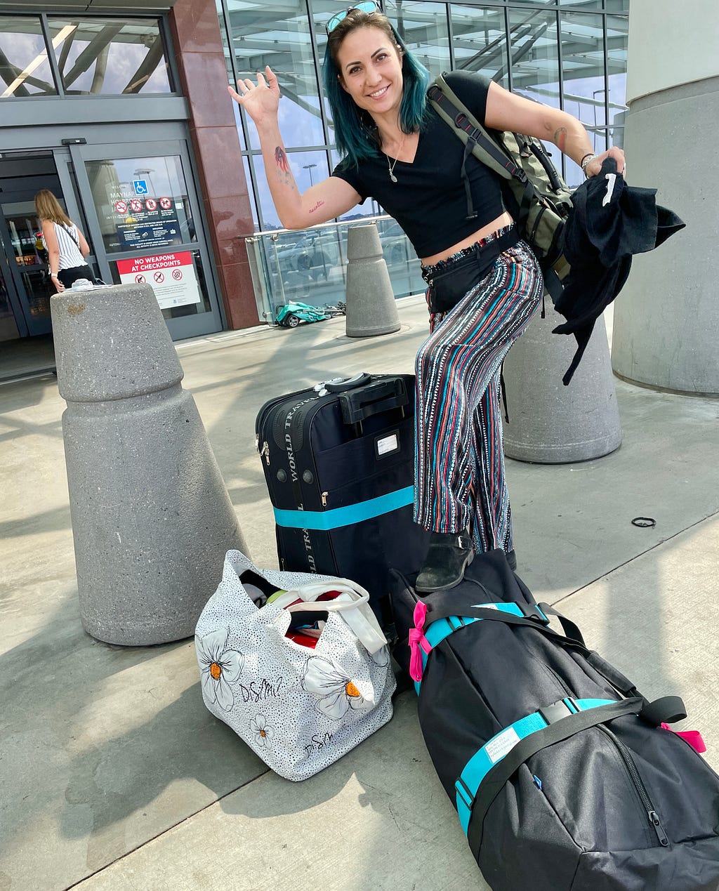 Woman waves goodbye at airport with large suitcases