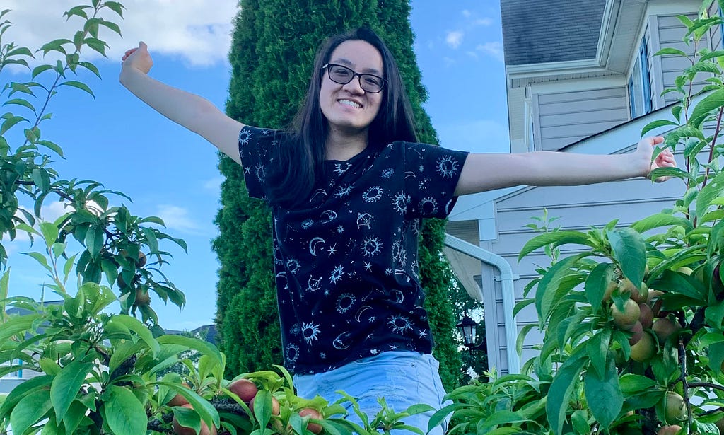 Caroline smiling while on top of a ladder with her arms raised