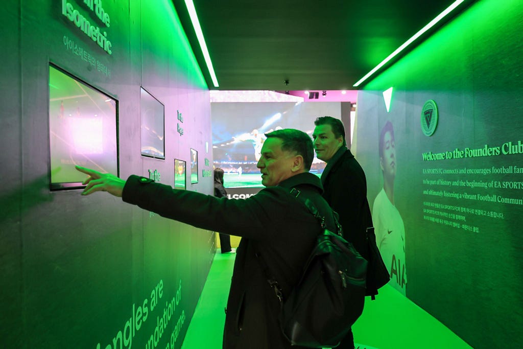 a man touches a screen on the wall in a tunnel for soccer game booth