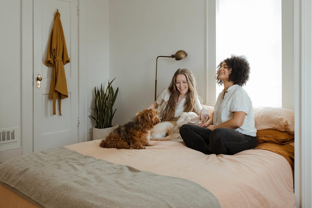 two women and a dog sitting on a bed