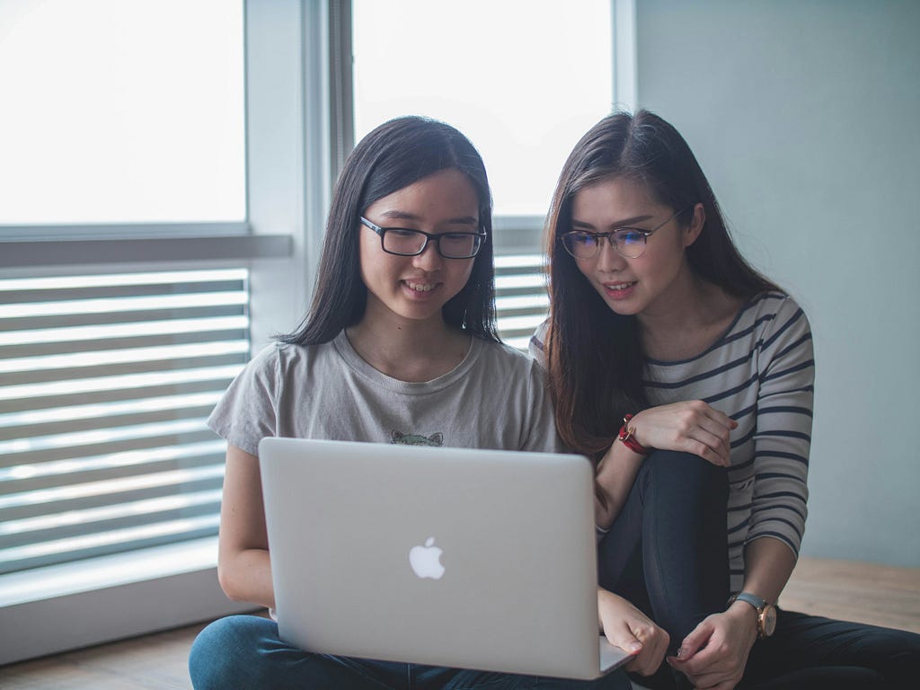 Two young women working in front of a computer