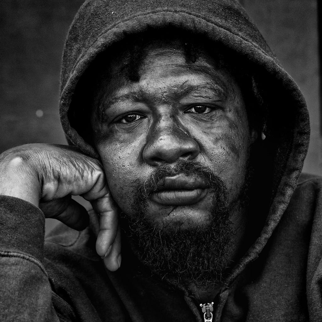 Black and white close up image of a mans face he wears a hoodie, hes face is scared. He has a goatee. The caption reads “Frank Frank (Image/Leroy Skalstad/Pixabay”