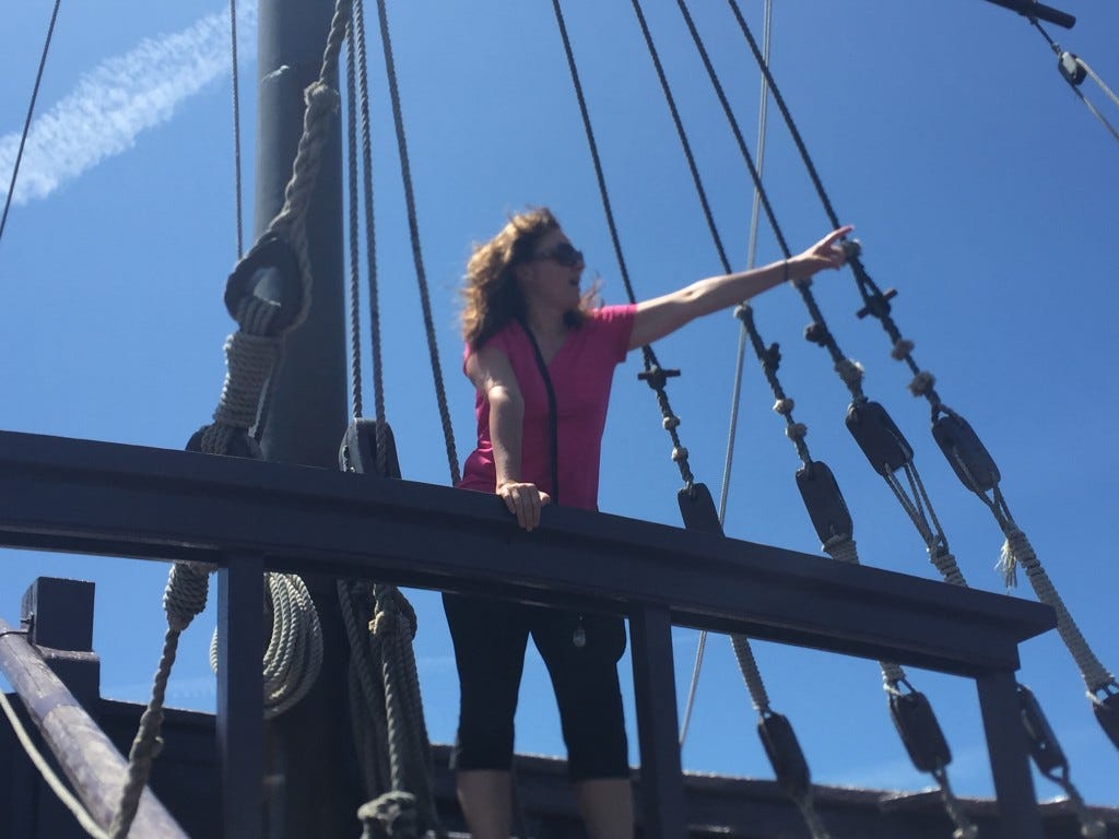 Michelle standing on the Caravel Pinta and pointing out to the horizon
