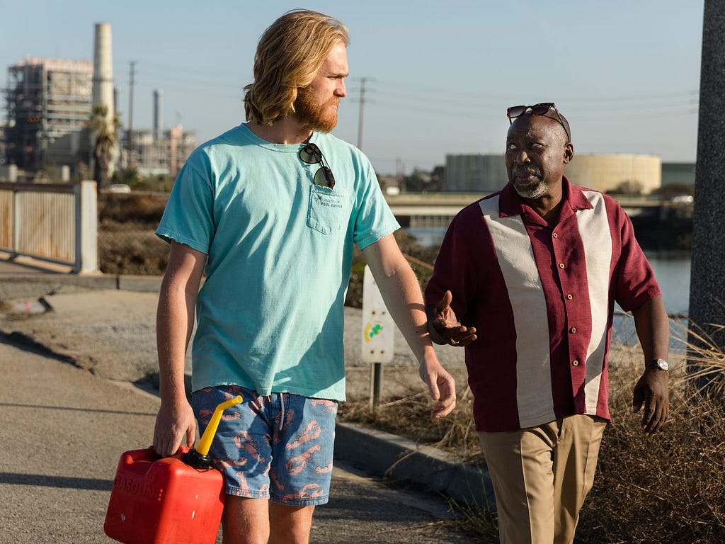 One white man and one Black man walking outside in the sun