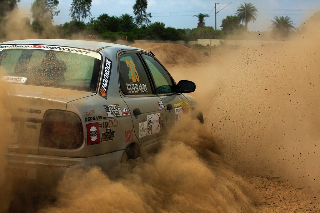 gray car covered in stickers drifting in sand