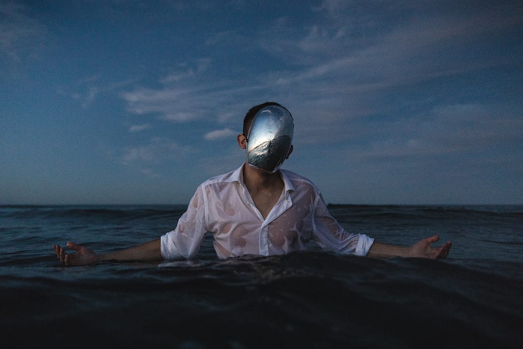 The mirror mask is a good metaphor to show how people put on a mask that they think other people want to see them wear. The ocean makes the concept deeply emotional; blue, thus sad; and intense.