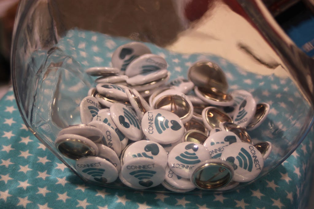 A glass bowl of pins that have an Uplift logo that says Connect