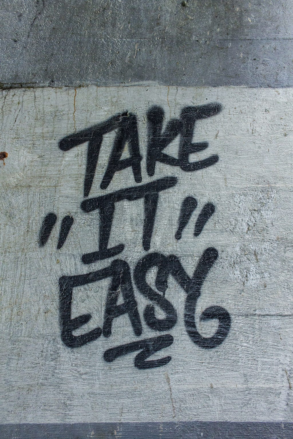A tag on a cement wall that reads, “Take it Easy”.