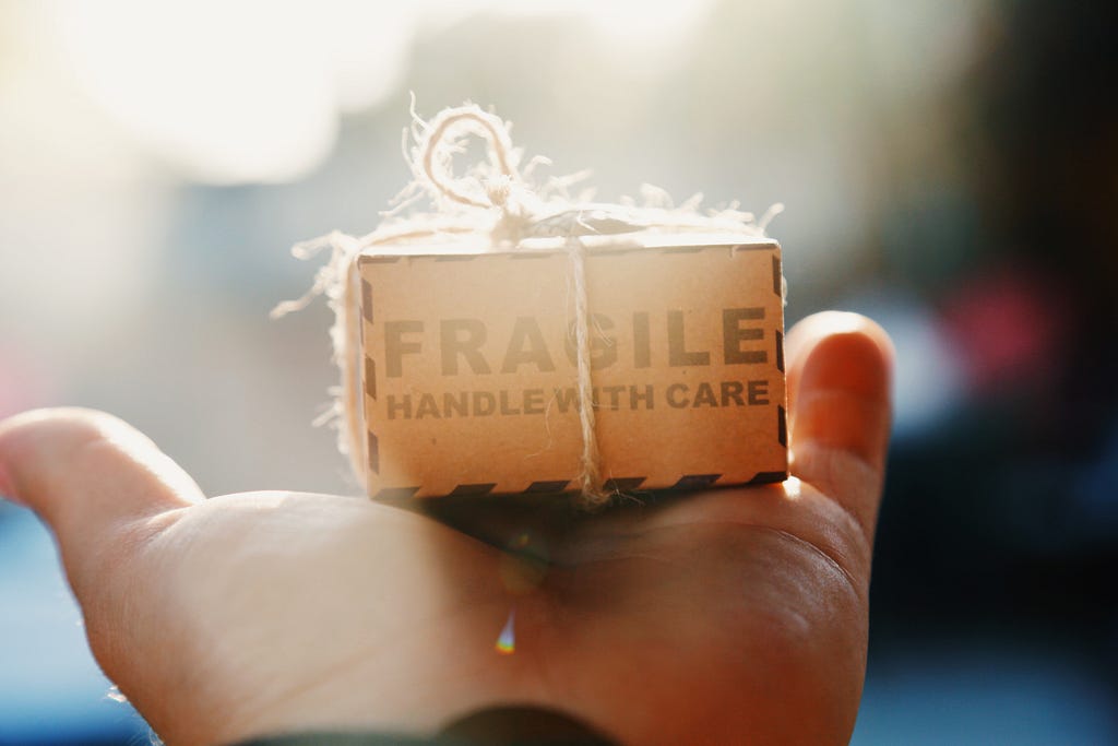 Small packaged box with fragile written on it resting on someone’s open palm