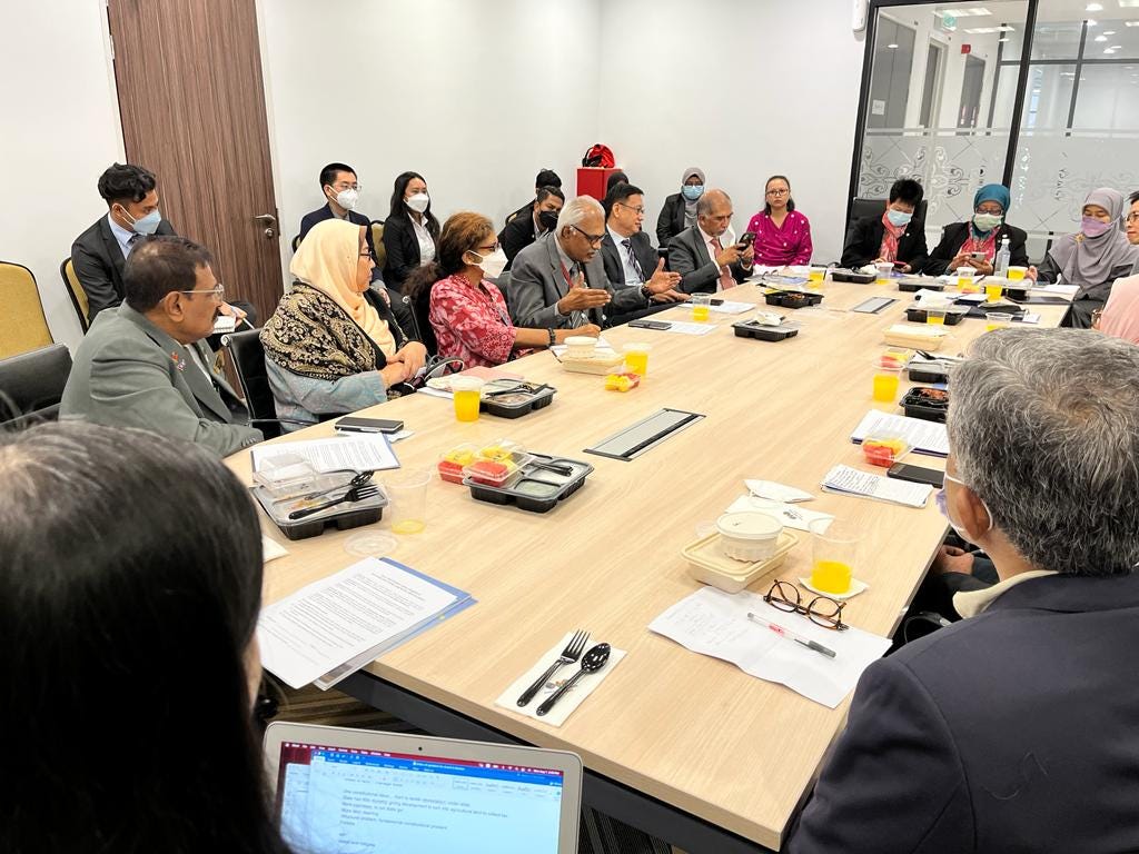 Around 15 individuals are sitting around the table. MP Charles Santiago is speaking. There are papers, food containers and cutlery on the table.