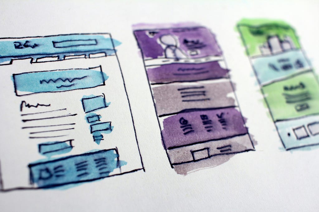 Colorful watercolor sketches of user interface wireframes on paper