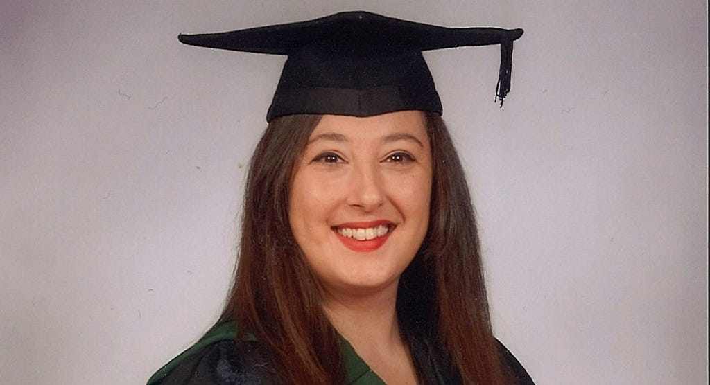An image of Robina in her graduation robes and wearing a square academic cap (or ‘mortarboard’)