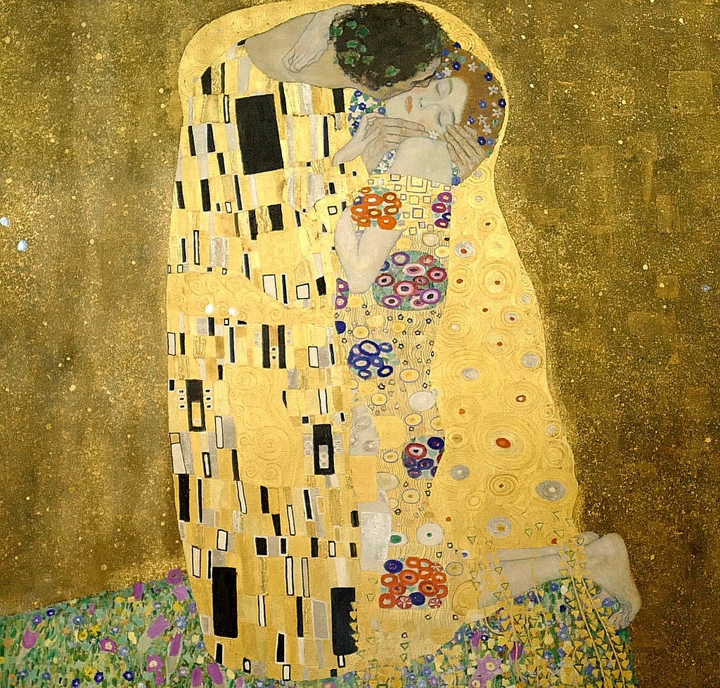 Gustave Klimt’s famous painting “the Kiss.” The two figures are in a very sensuous, erotic embrace, only their faces are visible, particularly the woman’s, whose eyes are closed suggesting immense pleasure. The figures are engulfed in a gold robe with geometric patterns. The background is a richly textured deep gold.