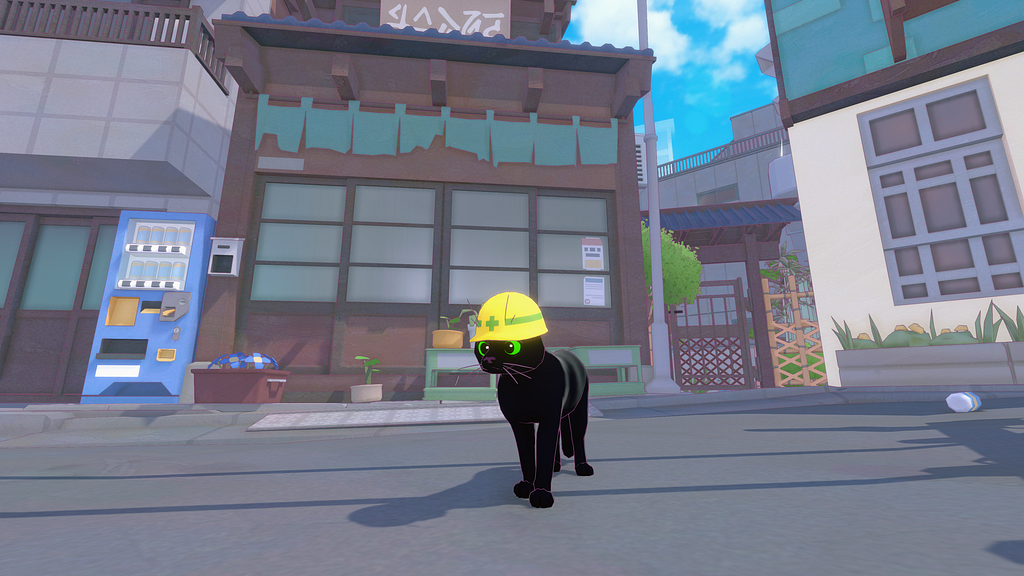 A mostly head-on image, slightly to the right, of the black cat with green eyes, wearing the same yellow hard hat with a green stripe. It’s in the road with a store behind it, and a blue vending machine to the left.