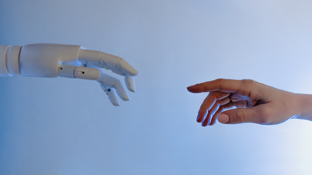 A robot and human hands reaching for eachother.
