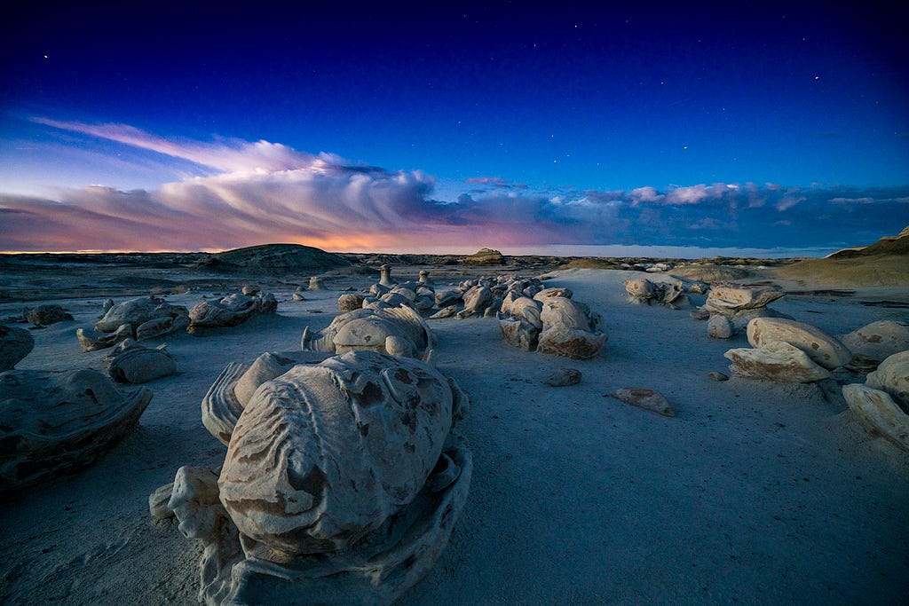 Formations in the foreground and clouds over the horizon in the background in the Bisti/De-Na-Zin Wilderness, located in northwestern New Mexico.