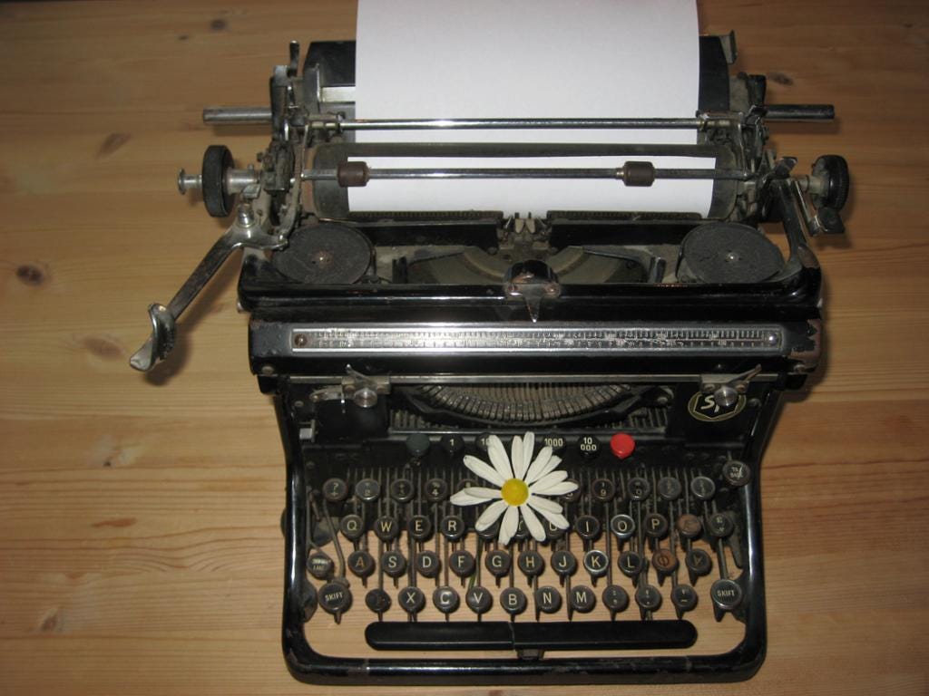 A photo of an old-fashioned typewriter with a daisy on it