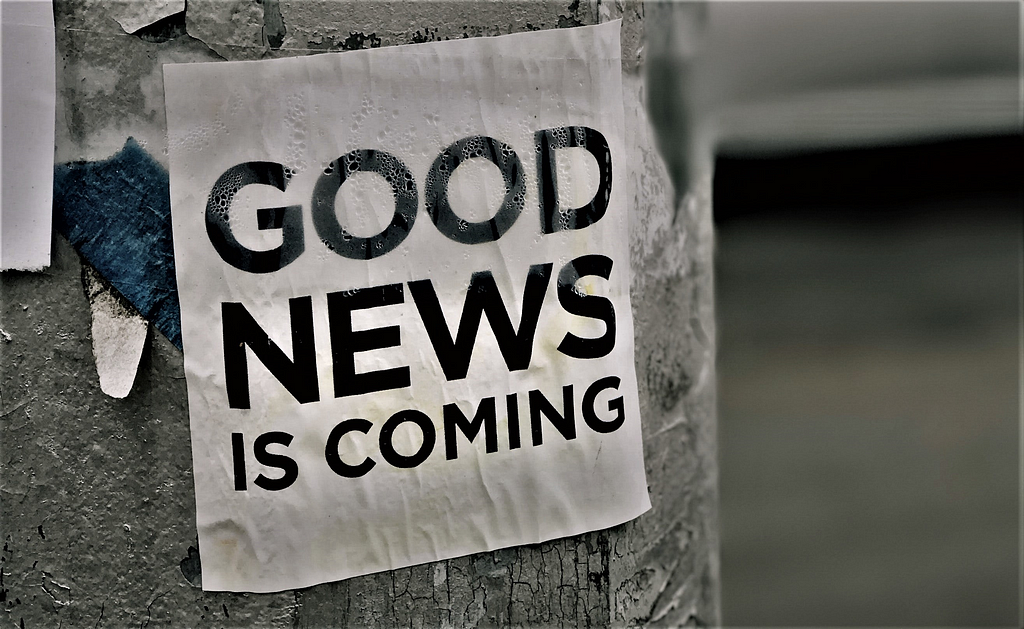 A laminated sign on a lamppost saying ‘GOOD NEWS IS COMING’